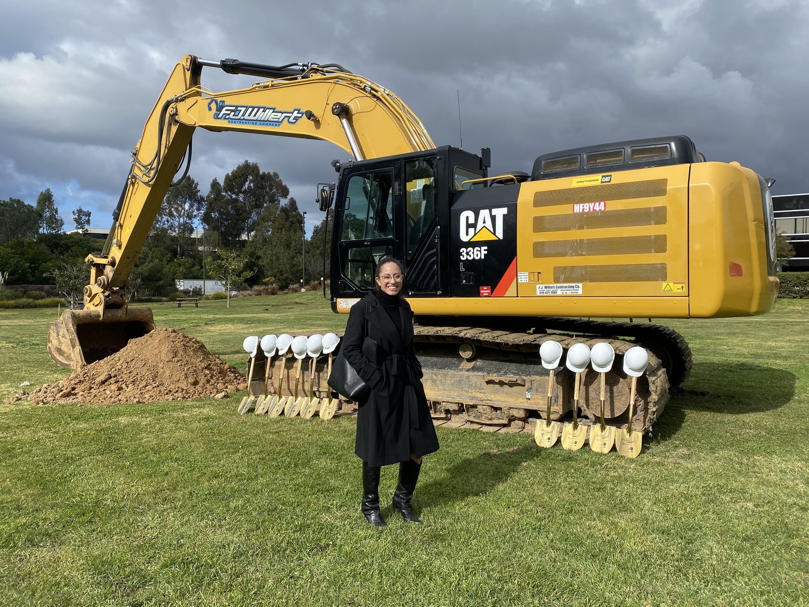Jessica on site at The Boardwalk groundbreaking in front of a CAT 336F excavator